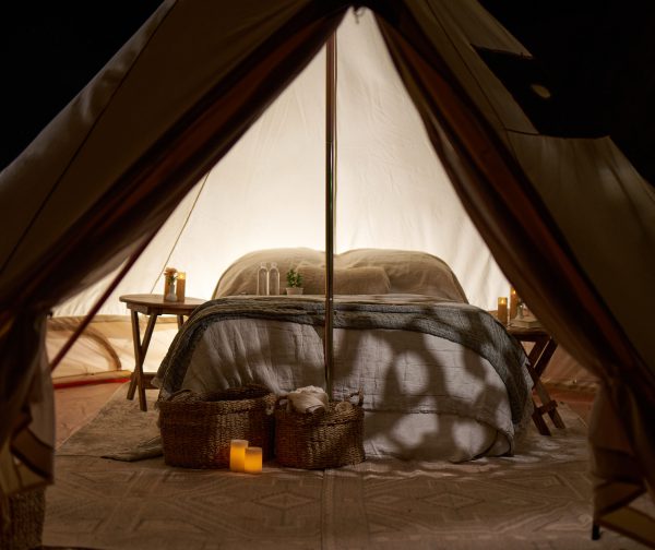 A detailed image of the inside of a glamping tent with a bed and table.